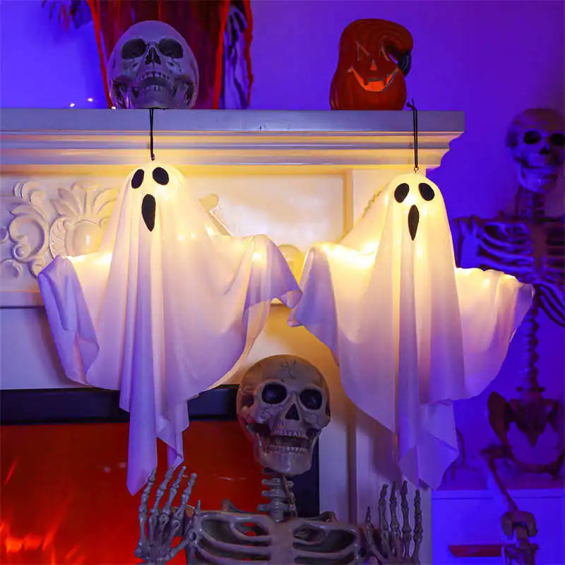 Light-Up Hanging Ghosts – two white sheet ghosts hanging from a mantel with skulls and skeletons