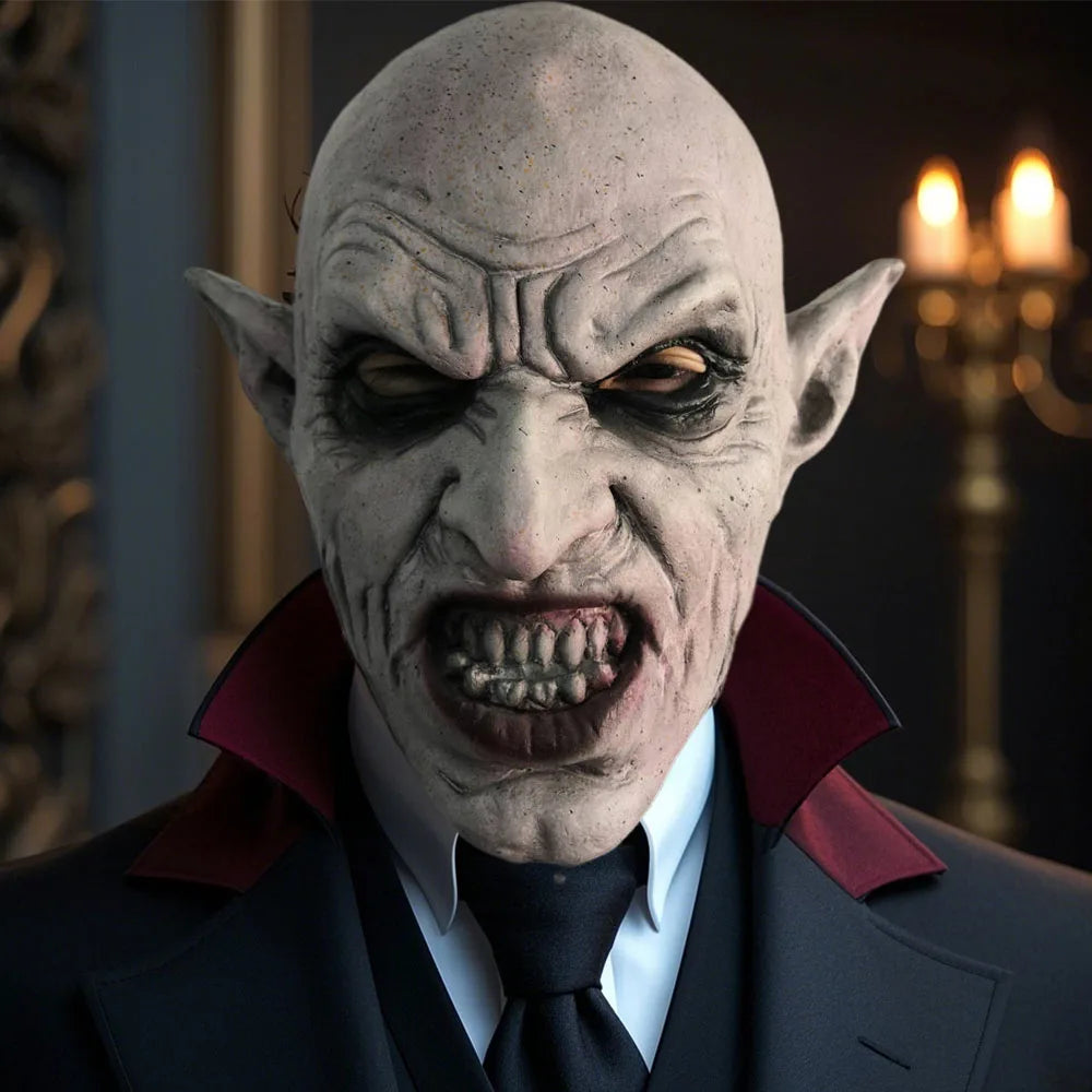 Vampire Latex Mask – pale bald vampire with pointed ears and snarling teeth, worn with a black suit and red-lined collar in a candlelit room