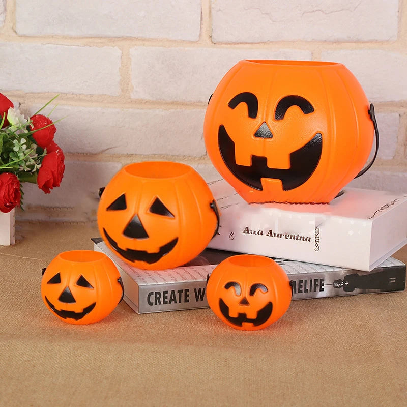 Jack-O'-Lantern Pumpkin Candy Bucket – four buckets styled on books and flowers against a brick wall